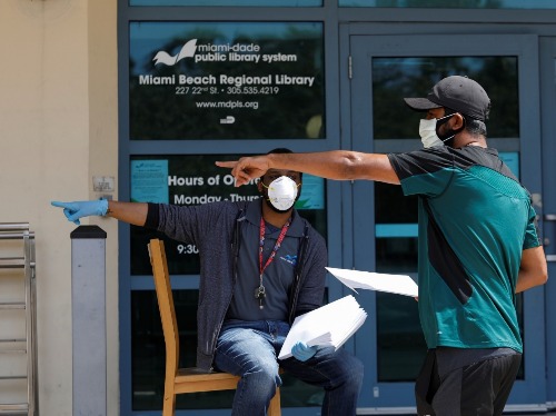 FILE PHOTO - A man speaks with a library worker after receiving an unemployment form, as the outbreak of coronavirus disease (COVID-19) continues, in Miami Beach, Florida, U.S., April 8, 2020. REUTERS/Marco Bello