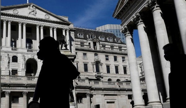 People wearing masks walk past the Bank of England, as the spread of the coronavirus disease (COVID-19) continues, in London, Britain, March 23, 2020.