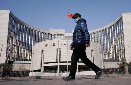 FILE PHOTO: A man wearing a mask walks past the headquarters of the People's Bank of China, the central bank, in Beijing, China, as the country is hit by an outbreak of the new coronavirus, February 3, 2020. REUTERS/Jason Lee